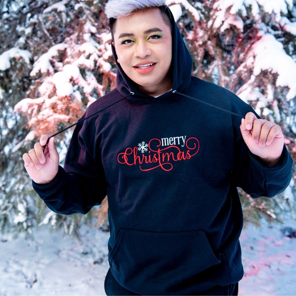 Male wearing a black hoodie embroidered with Merry Christmas in the front - DSY Lifestyle