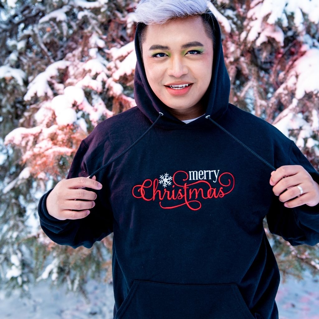 Male wearing a black hoodie embroidered with Merry Christmas in the front - DSY Lifestyle