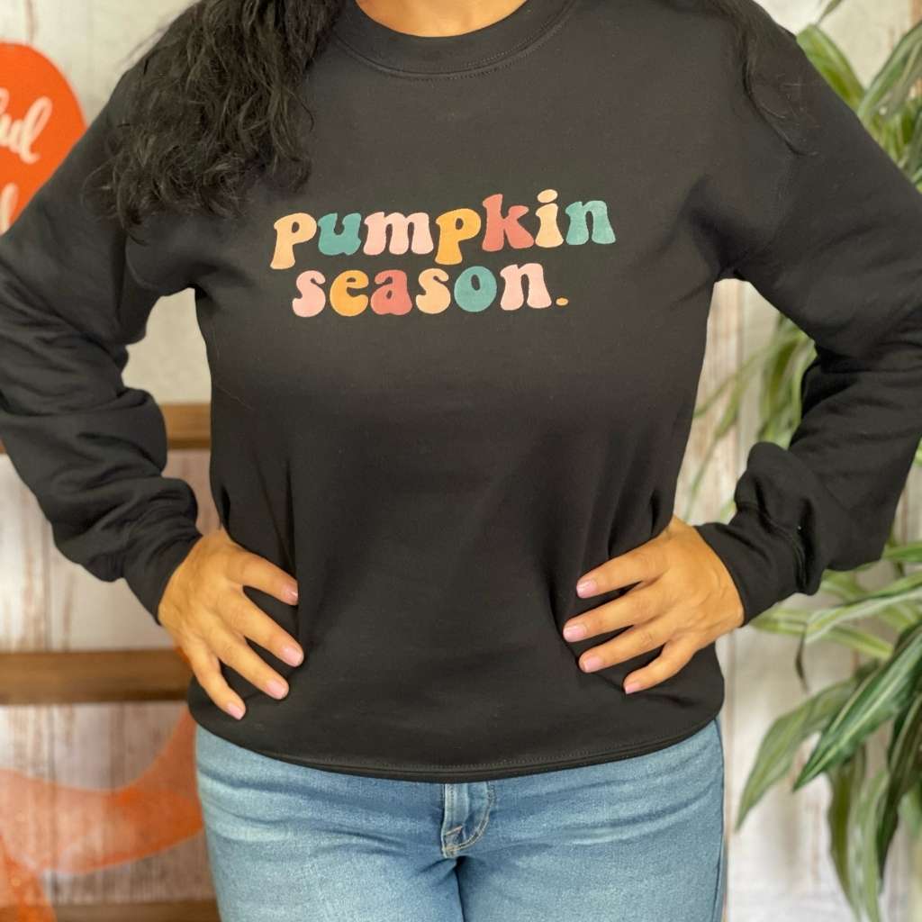 Female wearing a black crewneck sweatshirt printed with pumpkin season in the front - DSY Lifestyle