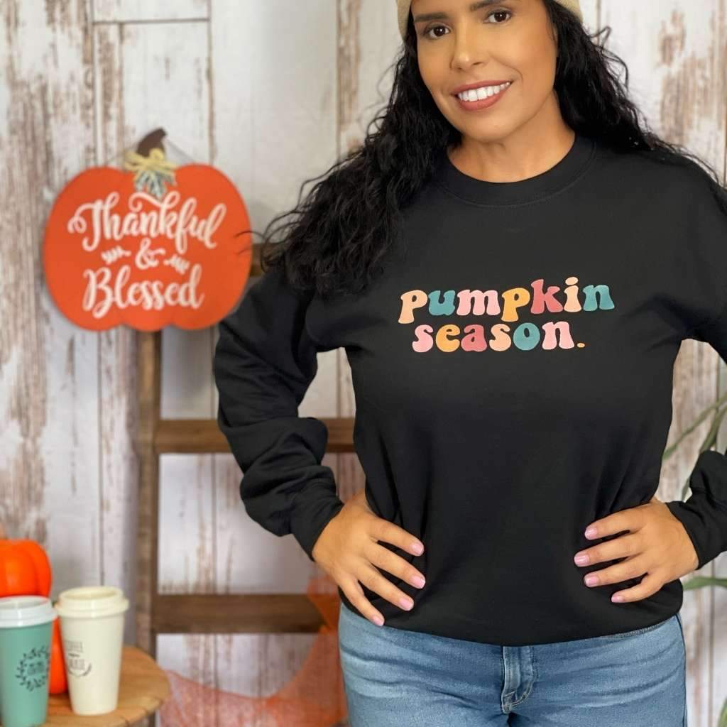 Female wearing a black crewneck sweatshirt printed with pumpkin season in the front - DSY Lifestyle