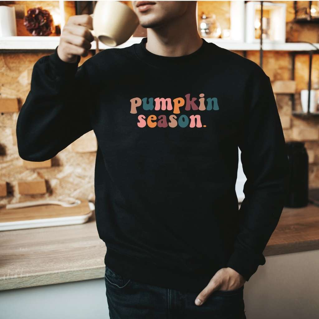 Male wearing a black crewneck sweatshirt printed with pumpkin season in the front - DSY Lifestyle