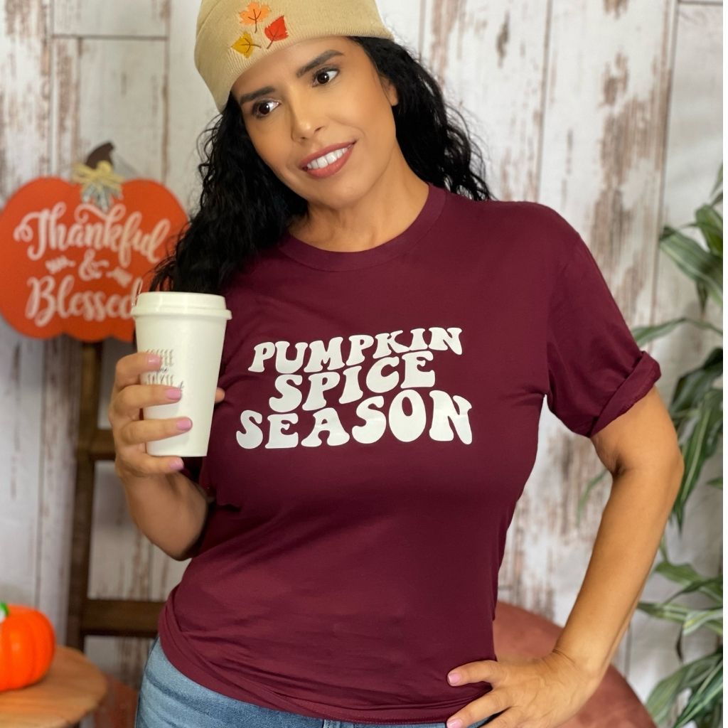 Female holding a coffee cup and wearing a burgundy tshirt with Pumpkin Spice Season printed in the front in white - DSY Lifestyle