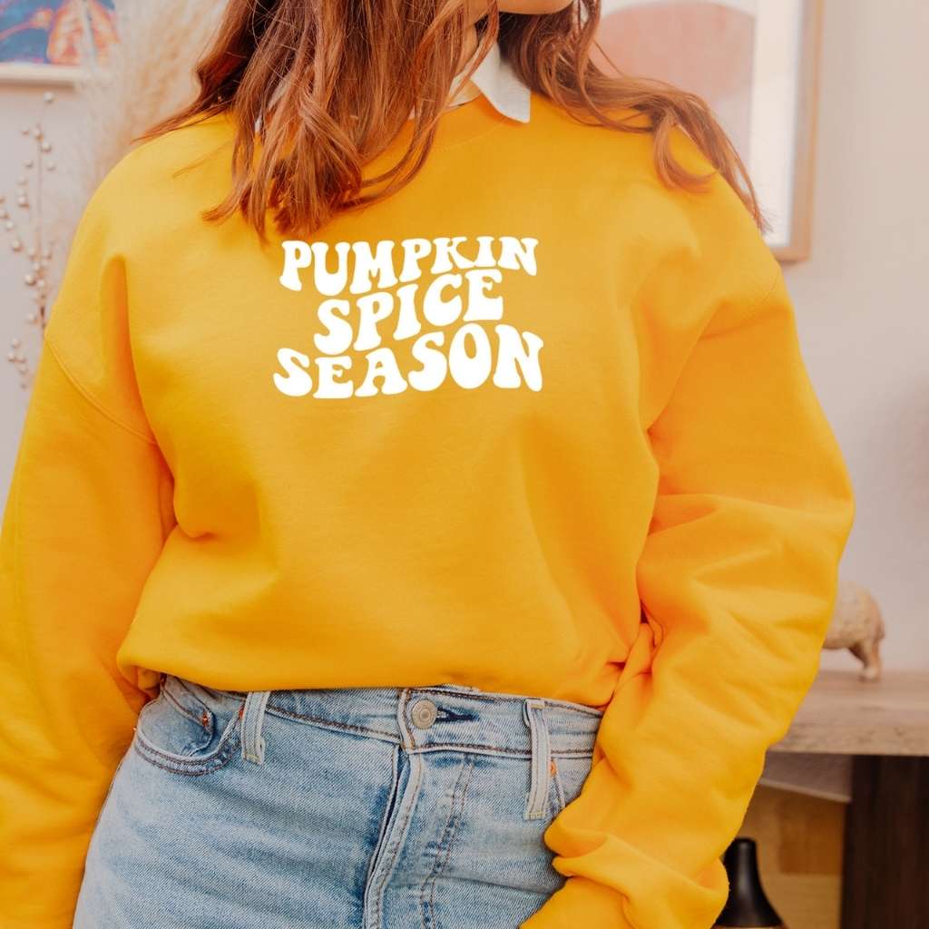 Female wearing a gold sweatshirt with pumpkin spice season printed in the front in white - DSY Lifestyle