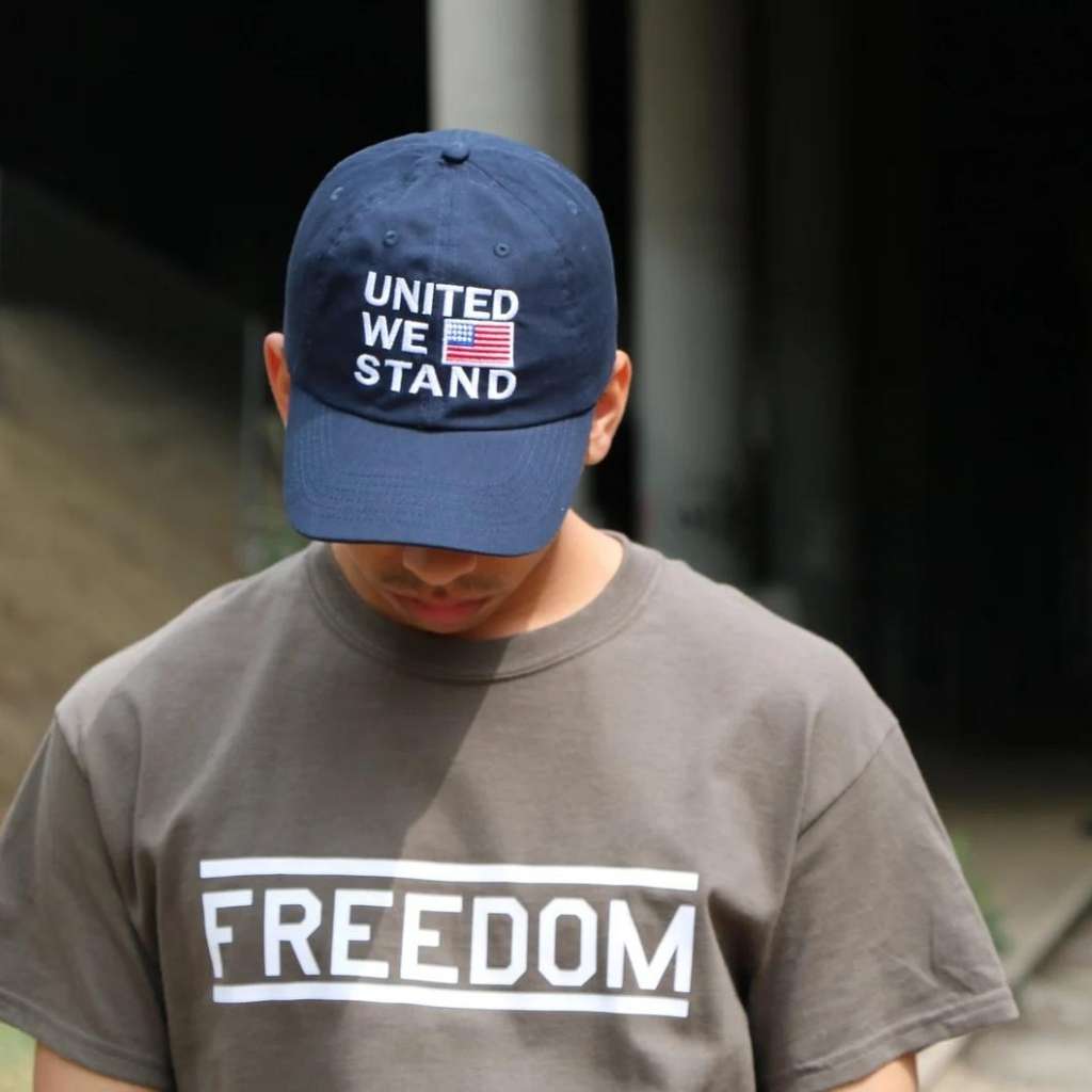 Male wearing a navy blue baseball cap embroidered with the USA Flag and United we stand - DSY Lifestyle