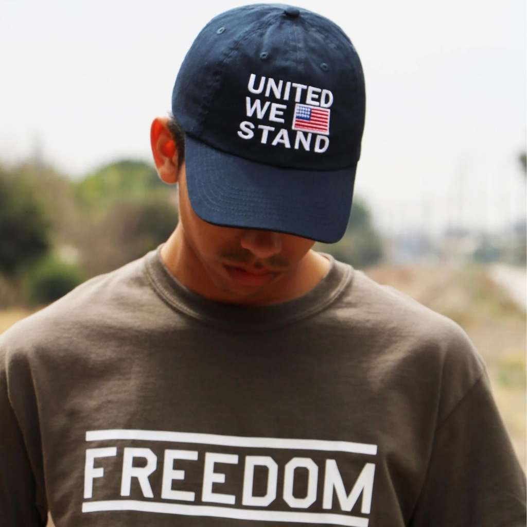 Male wearing a navy blue baseball cap embroidered with the USA Flag and United we stand - DSY Lifestyle