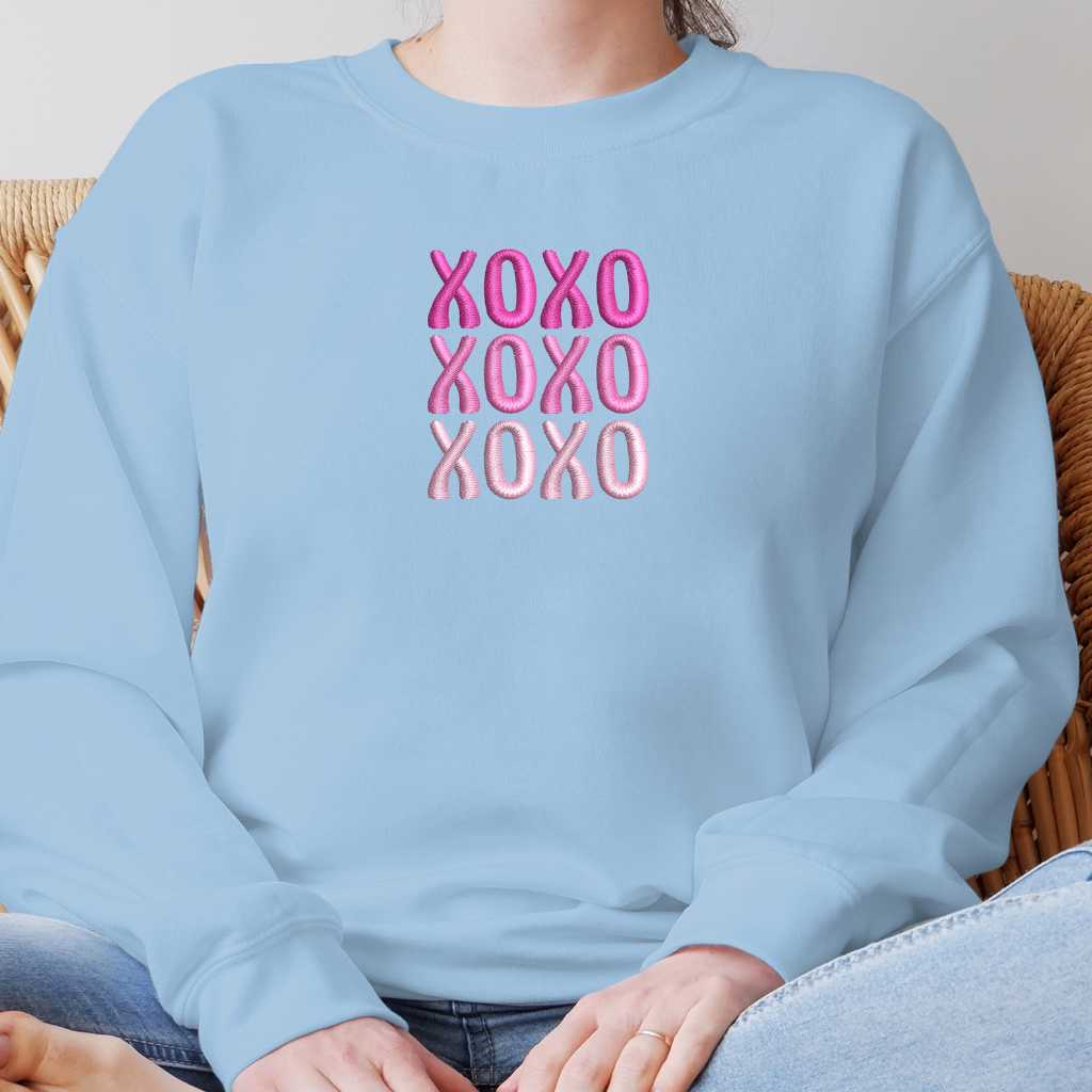 Female wearing a sky blue sweatshirt embroidered with XOXO in shades of Pink - DSY Lifestyle